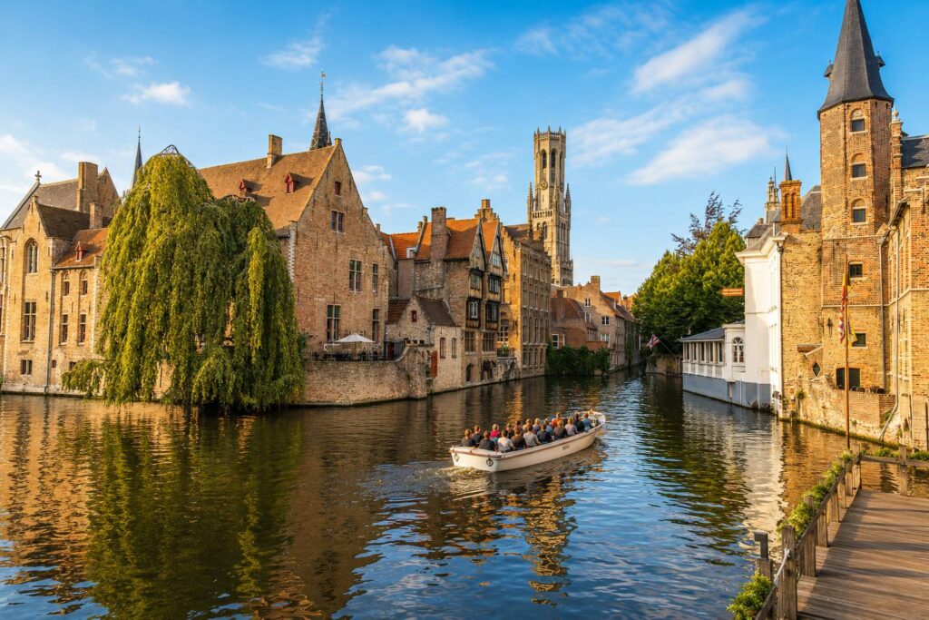 Brugge gracht met boot in het historische centrum Zonnige gracht in Brugge met historische gebouwen, een rondvaartboot en natuurlijke reflecties op het water